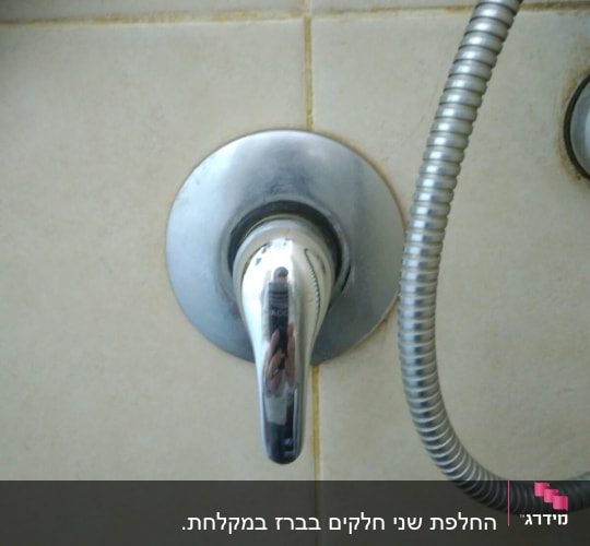 ברז כרום עם צינור מתכת על קיר אריחים